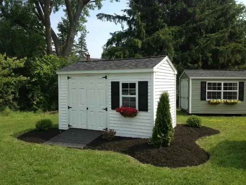 A white shed with flowers on the window.