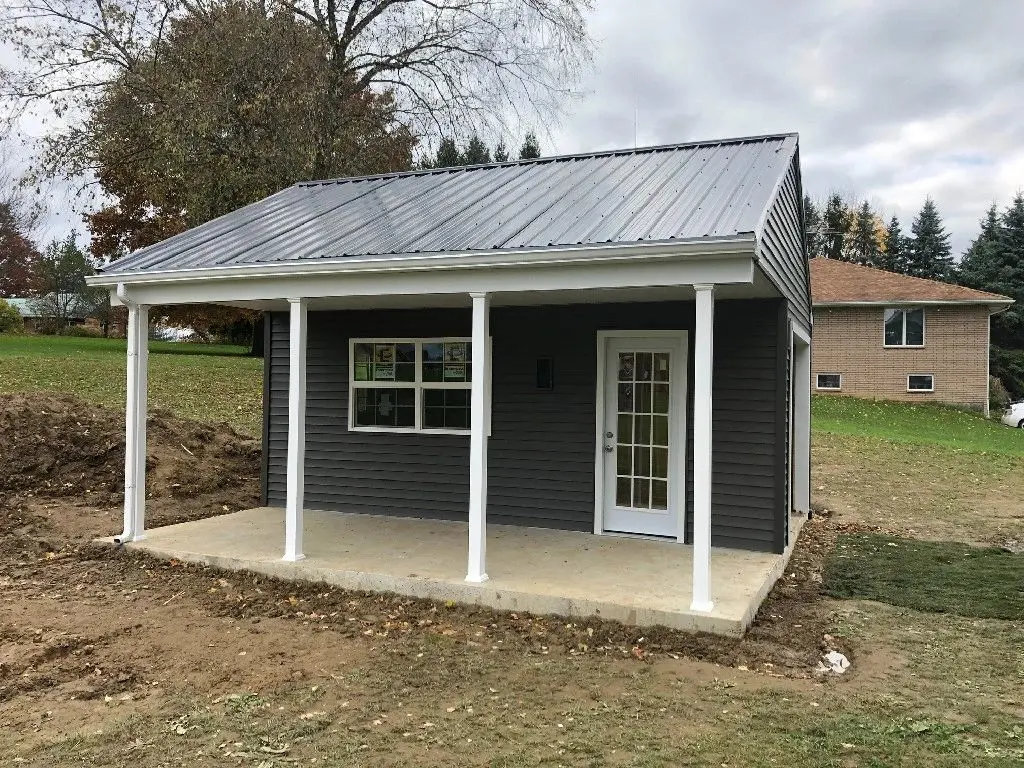 A small shed with a porch and metal roof.