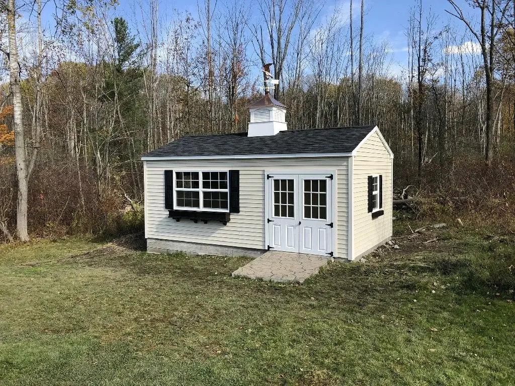 A white shed with black roof and windows.