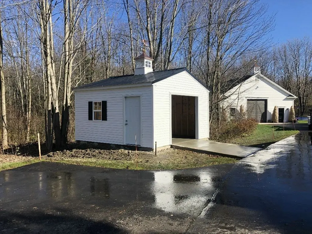 A white shed sitting on the side of a road.