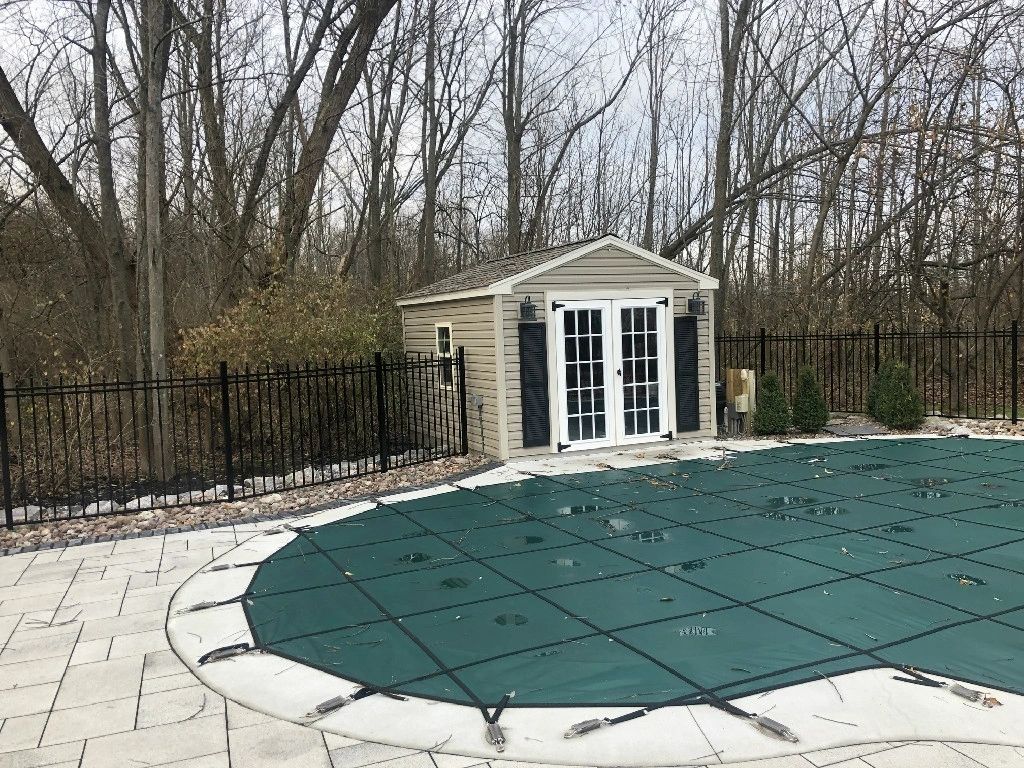 A pool cover is in the middle of a backyard.