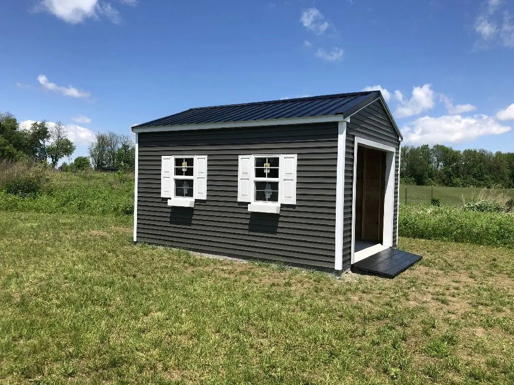 A black and white shed in the middle of a field.