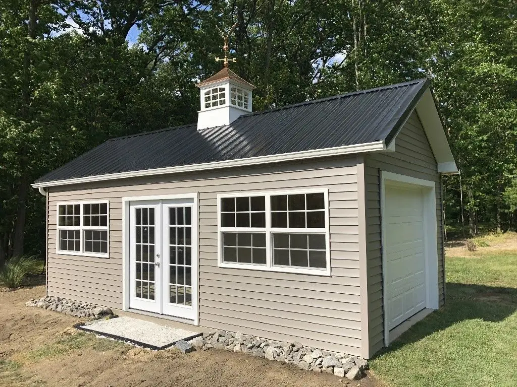 A shed with a black roof and white doors.