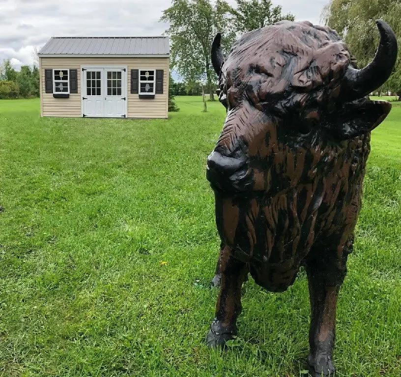 A statue of an animal in the grass near a building.