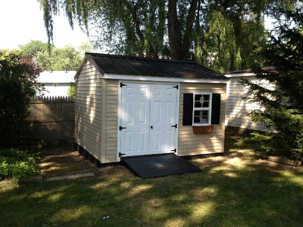A white shed with two windows and black shutters.