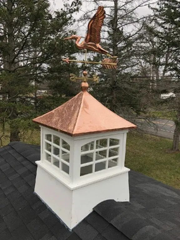 A white and gold cupola with a bird on top of it.