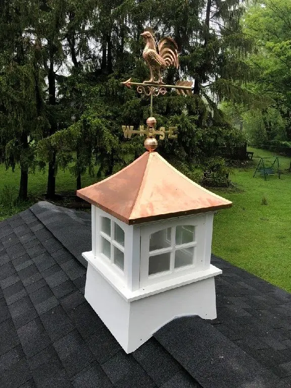 A white and gold cupola with a weather vane on top.