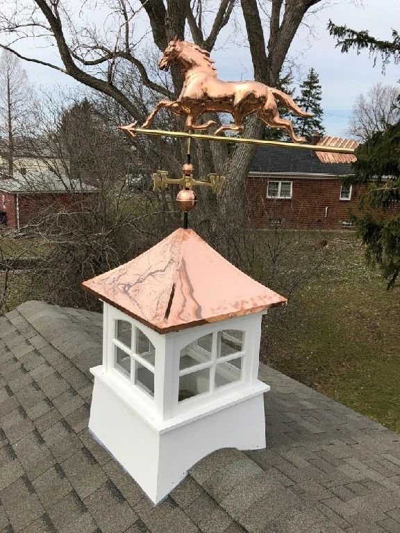 A horse weathervane on top of a white cupola.