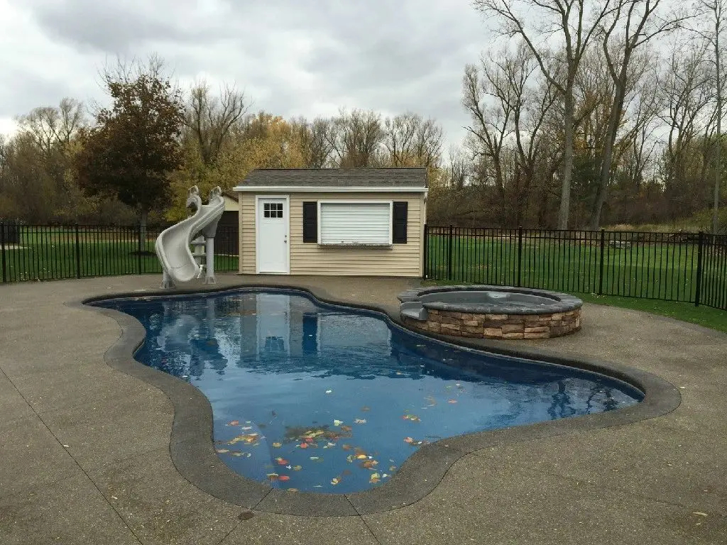 a shed next to a swimming pool with a slide