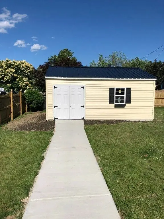 A white door and walkway leading to a shed.
