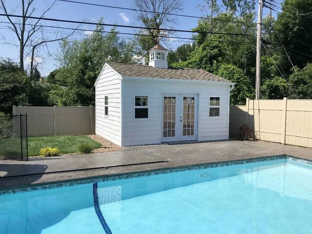 A pool house with a white roof and two windows.