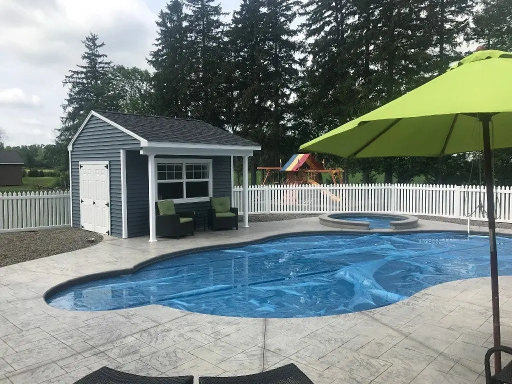 A pool with a cabana and swing set in the background.