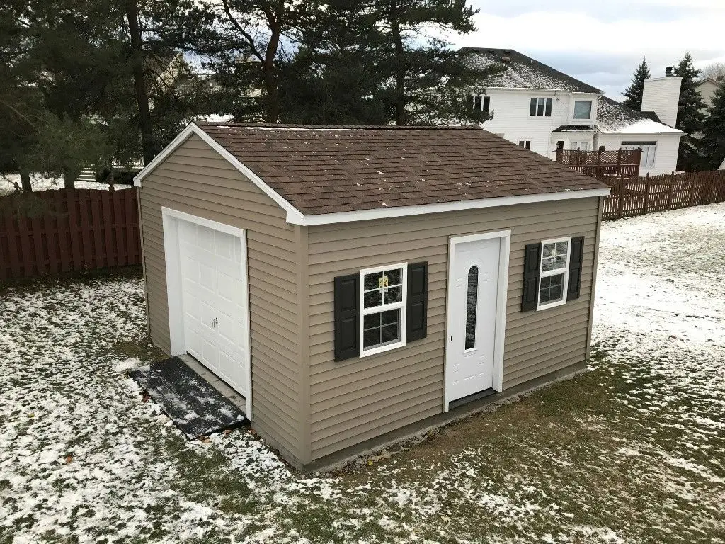 A shed with shutters and a door in the middle of a yard.