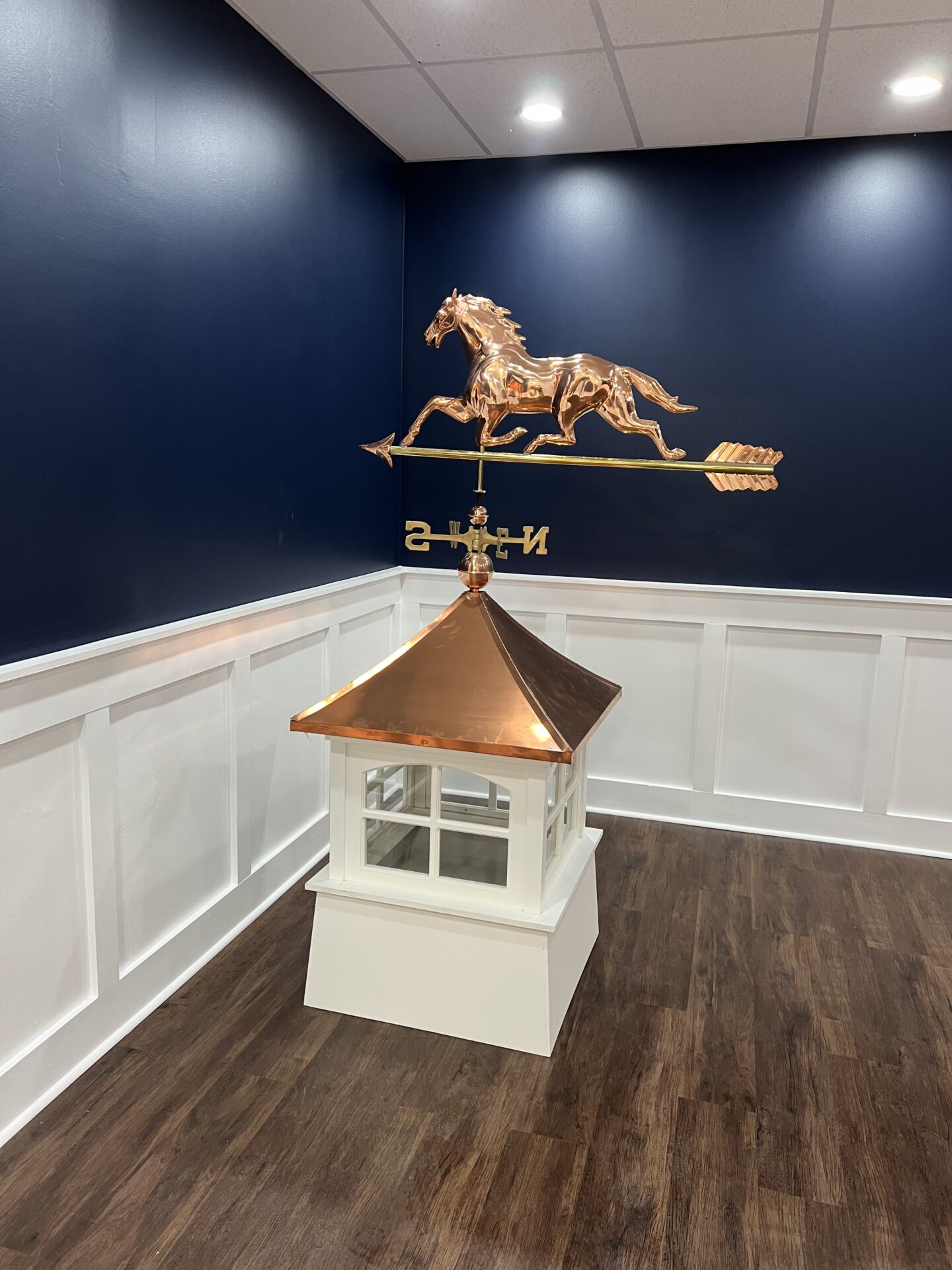 A white and gold cupola with a horse on top of it.