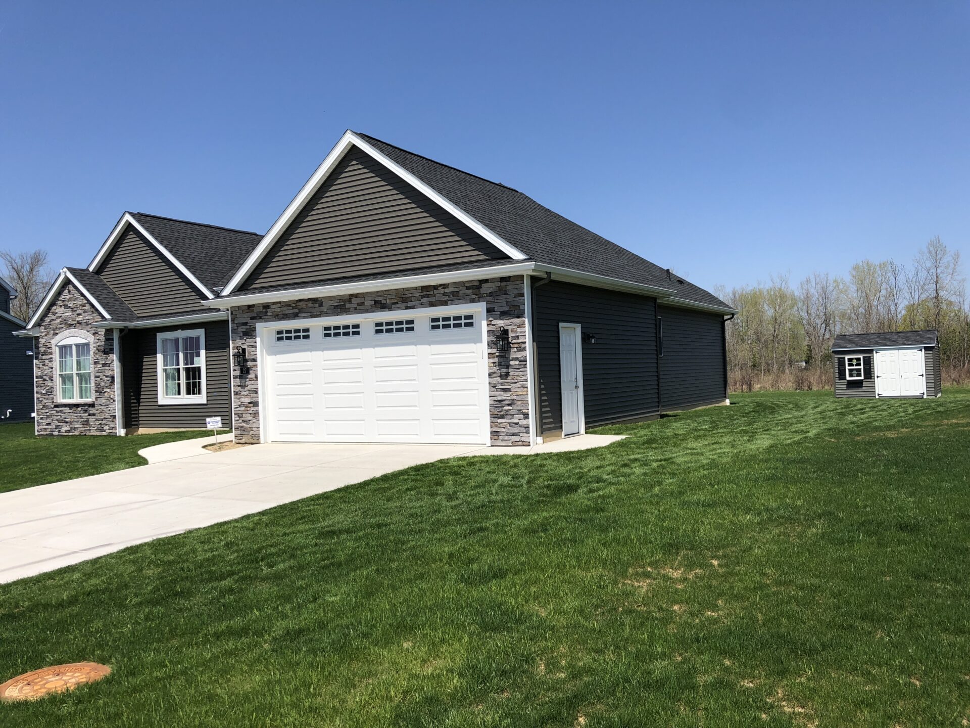 A house with two garage doors and grass in front of it.