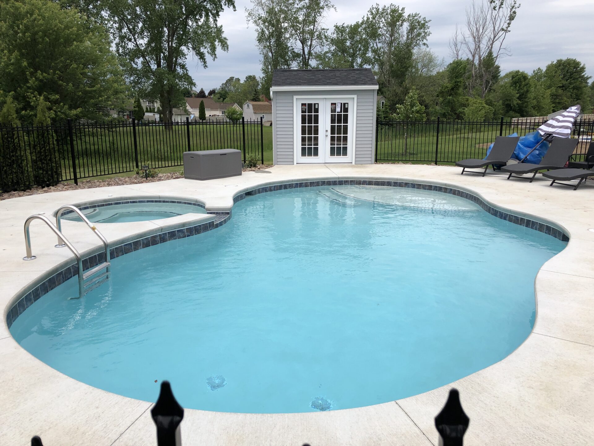 A pool with a jacuzzi and a fence