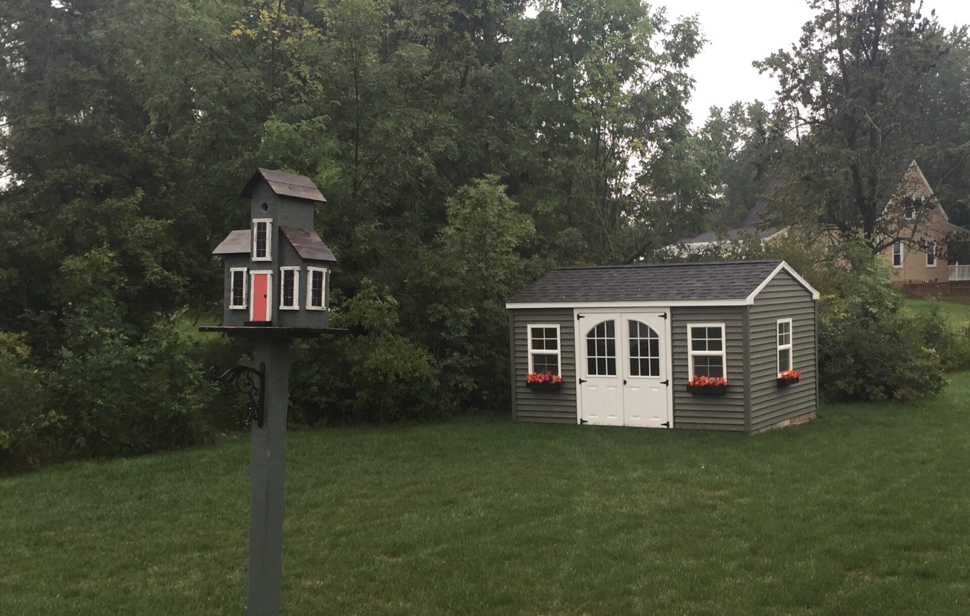 A birdhouse in the middle of a yard.