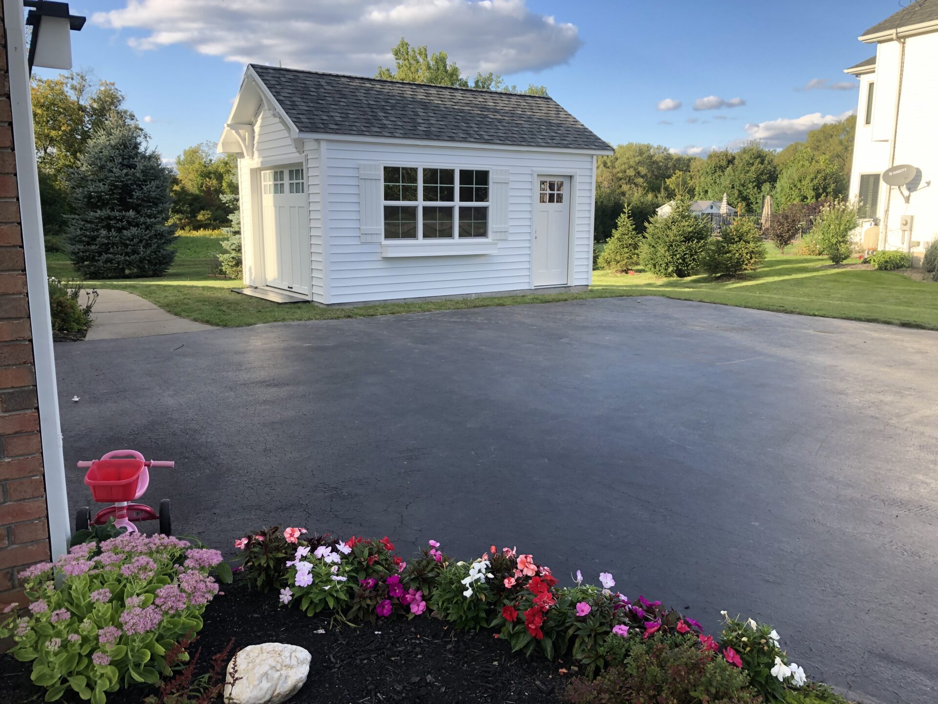 A white shed sitting in the middle of a driveway.