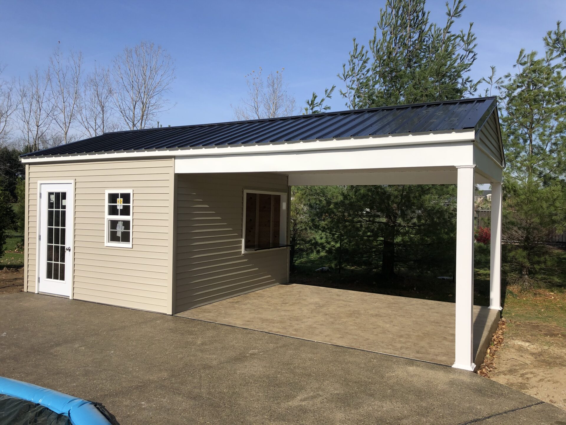 A carport with a metal roof and two windows.