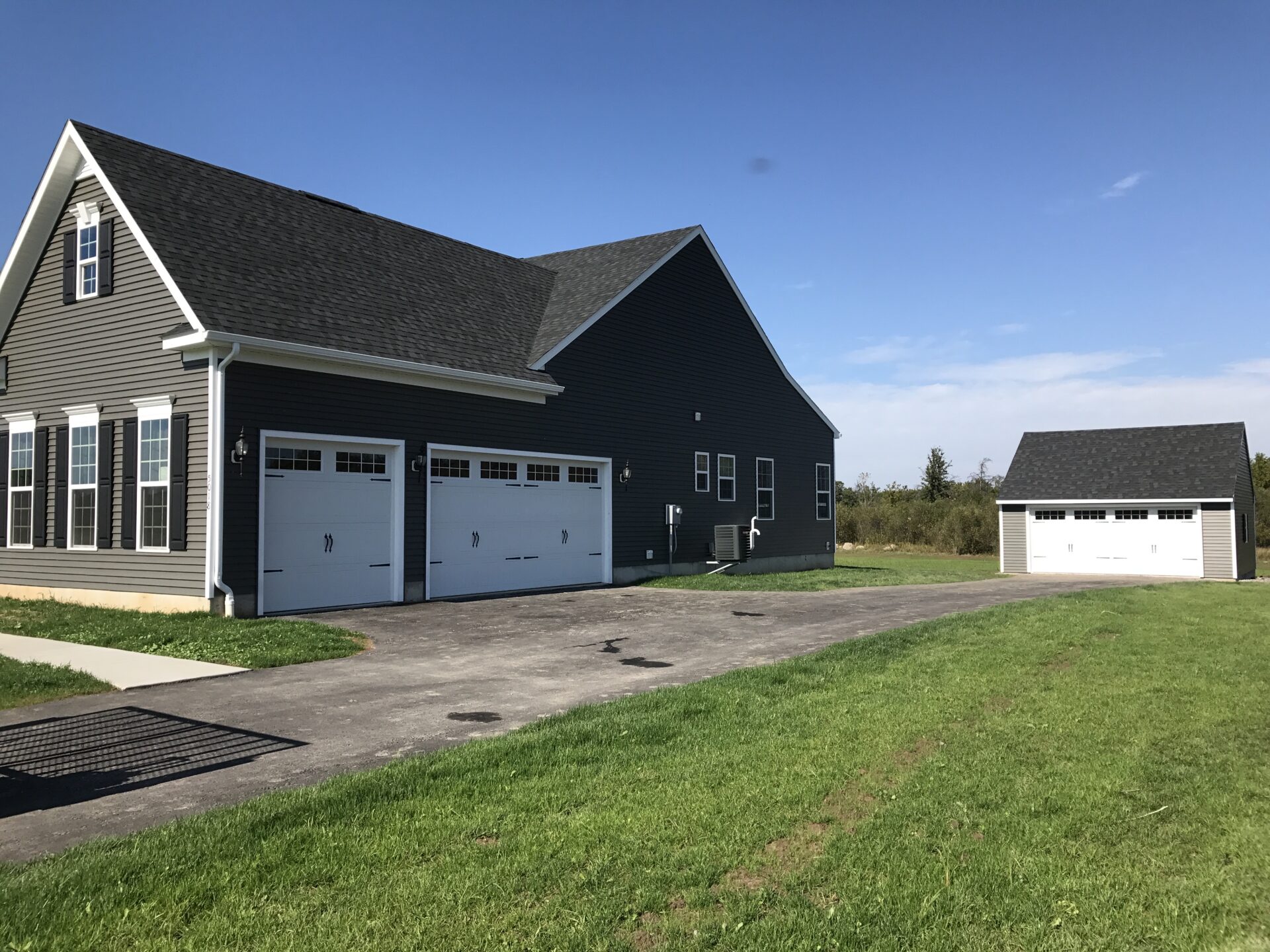 A large black house with two white garage doors.