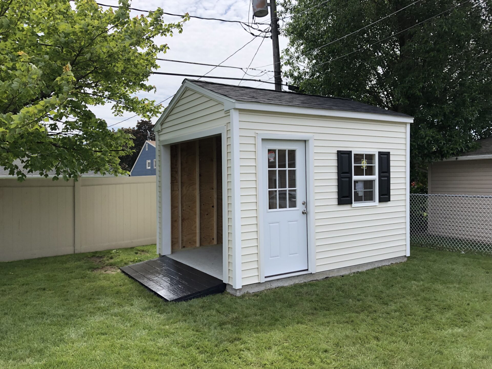 A white shed with black shutters and a ramp.