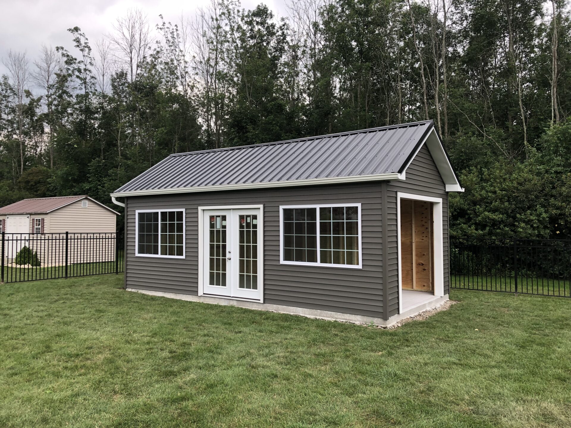 A shed with windows and doors in the middle of a field.