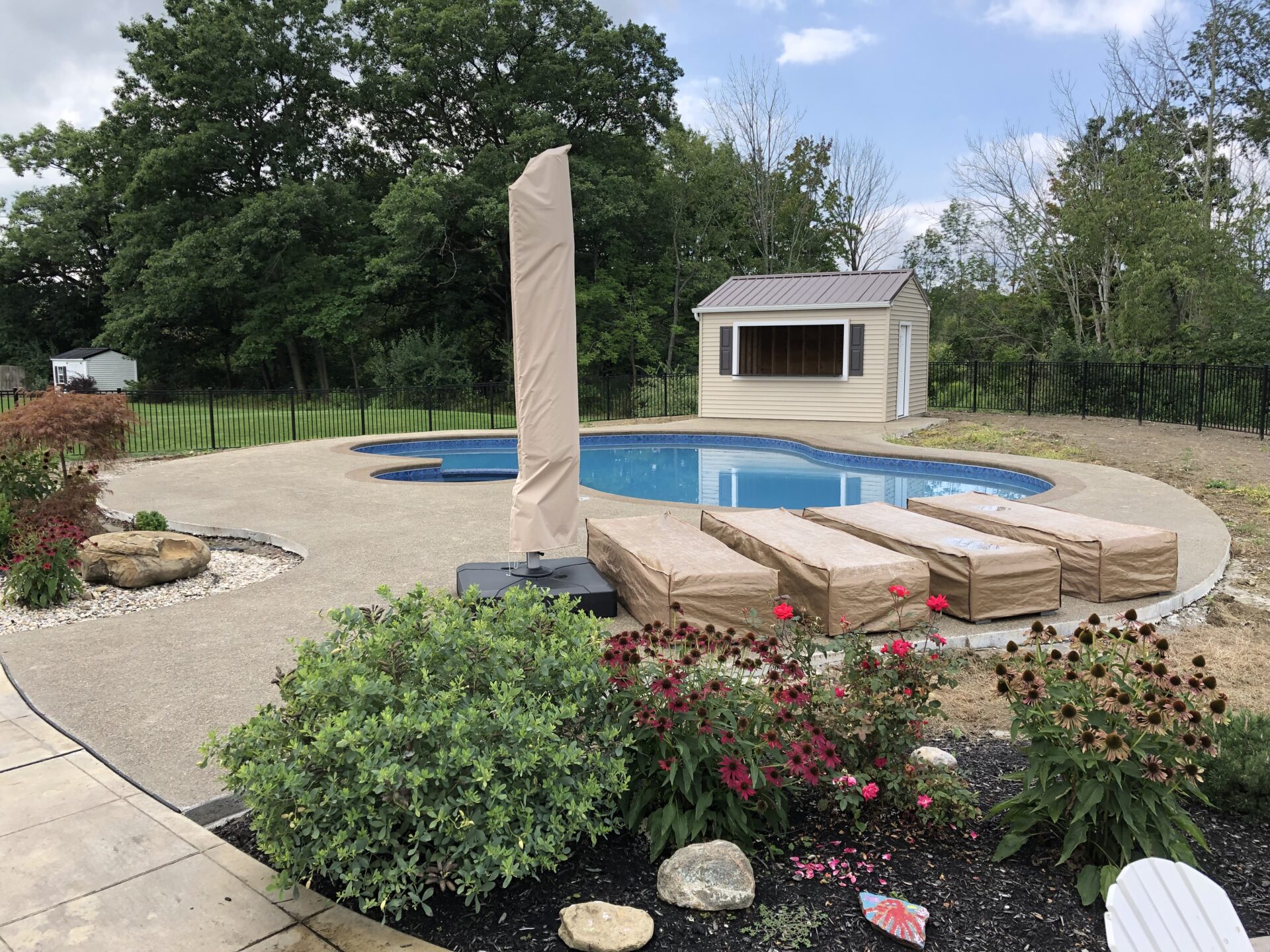 A pool with a large shade structure and a gazebo.