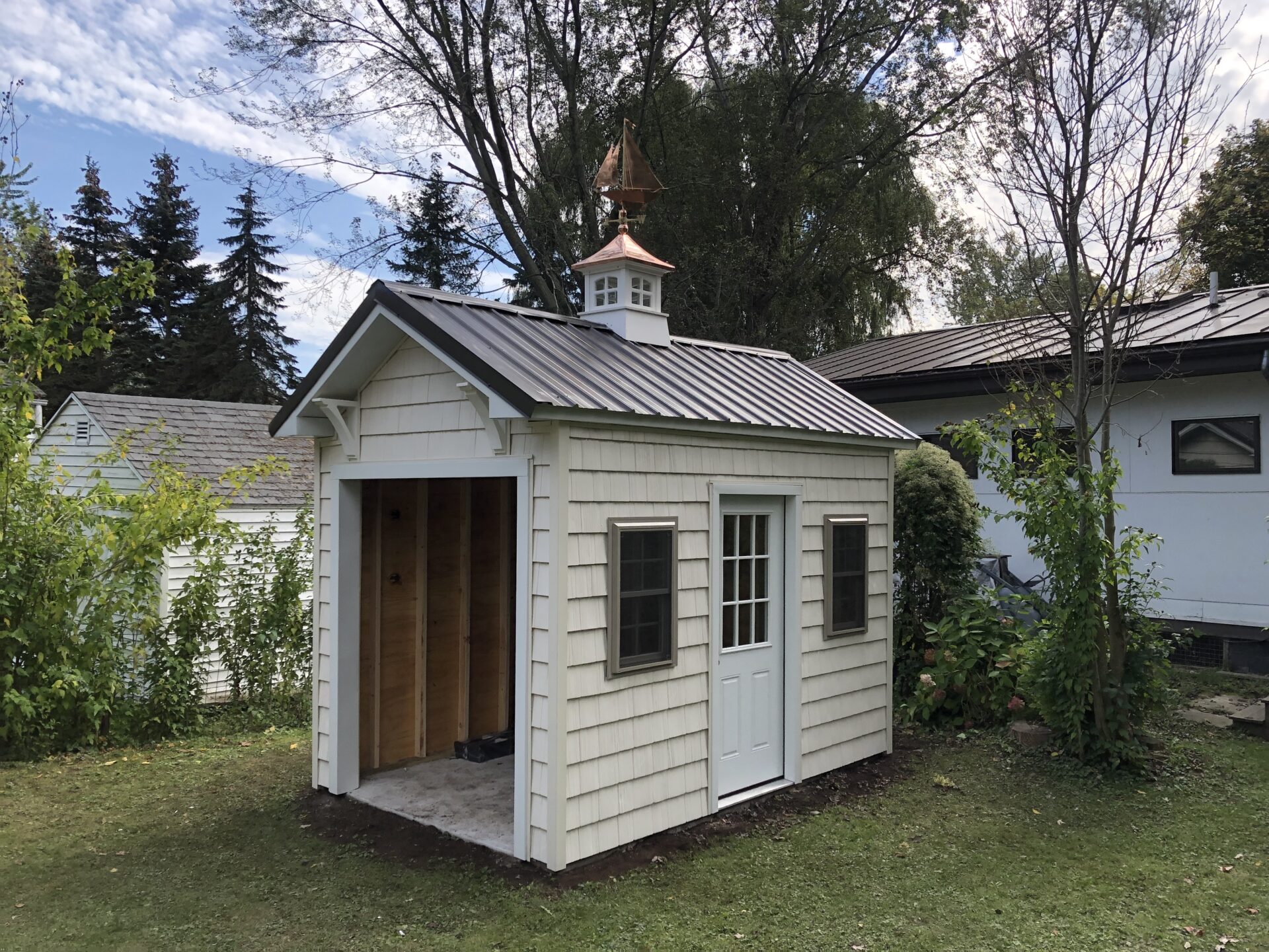 A small white shed with a metal roof.