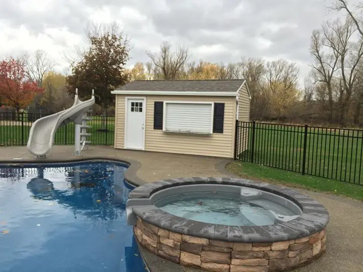 A pool with a slide and a hot tub in the middle of it.