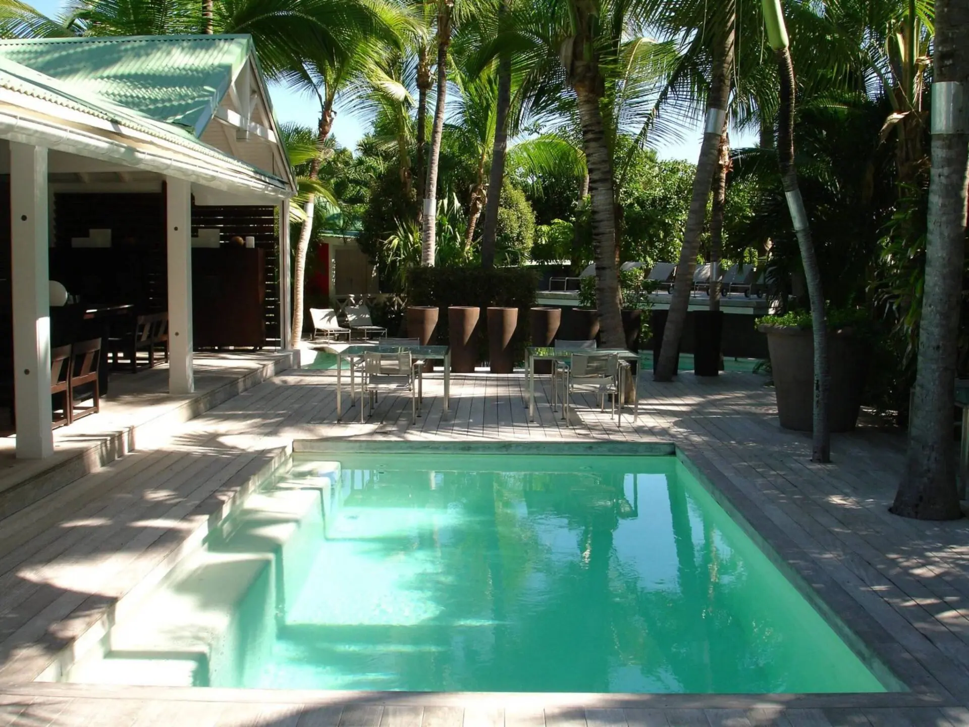 A pool with chairs and tables in the background.