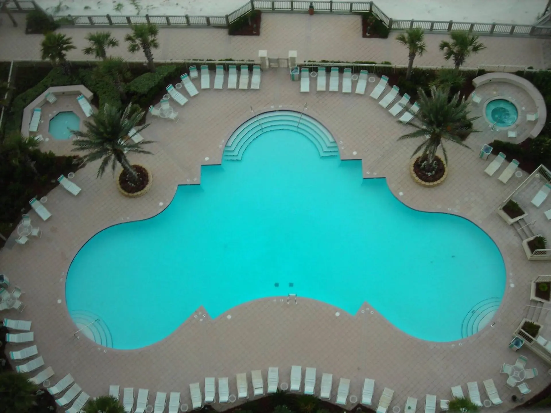 A pool with many chairs and trees in the background