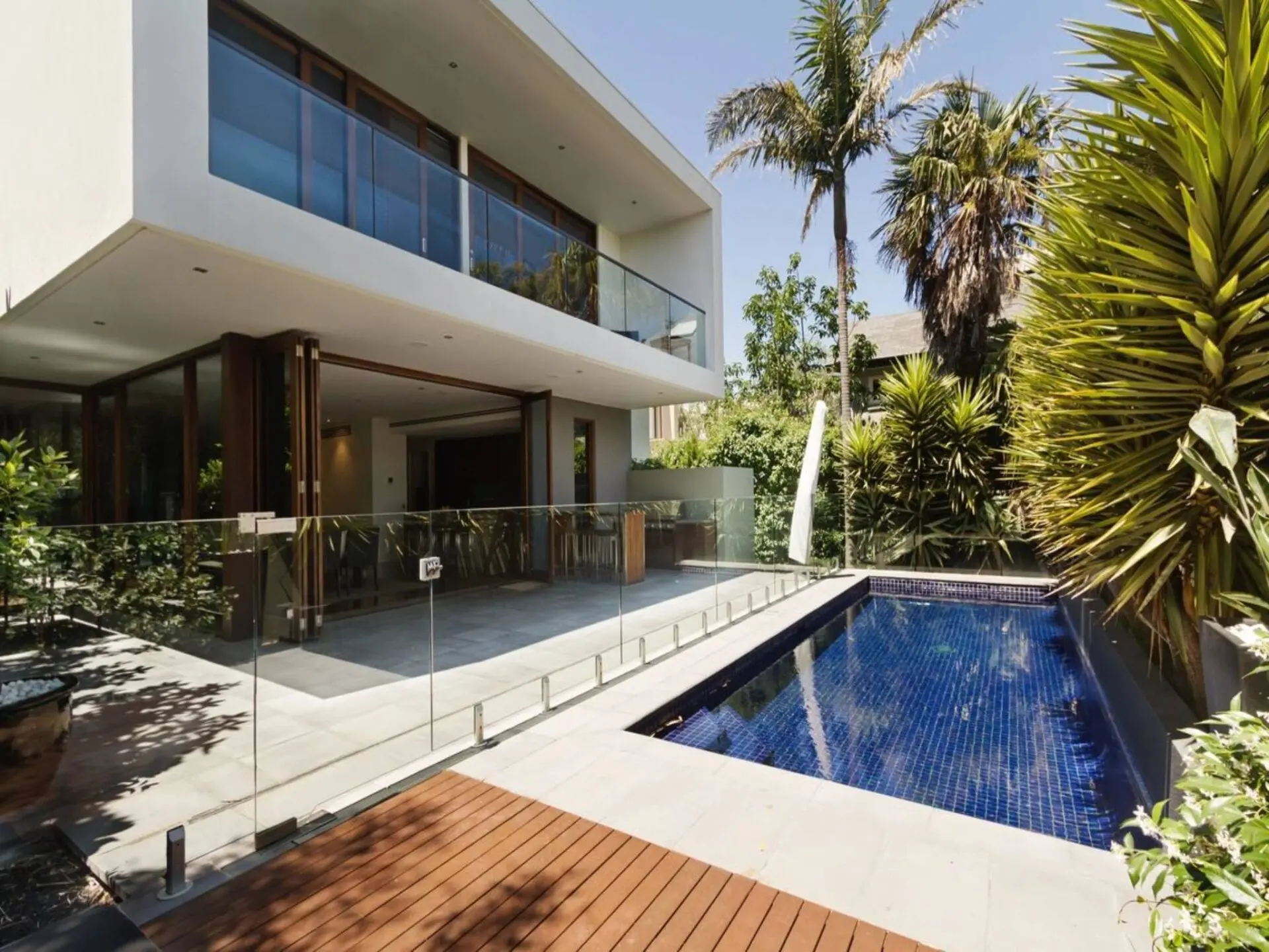 A pool in the middle of a house with palm trees.