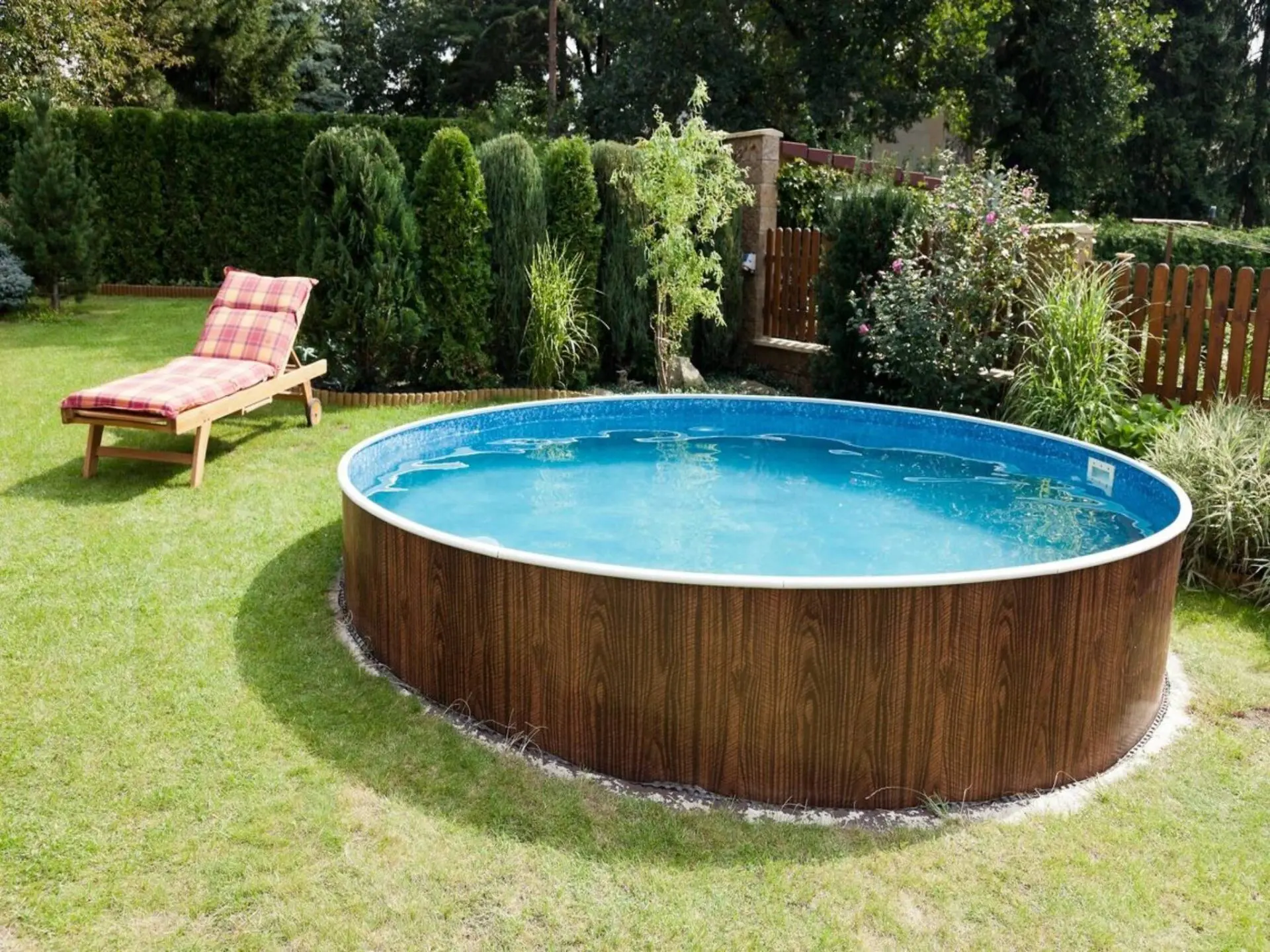 A pool in the middle of a yard with a lawn chair.