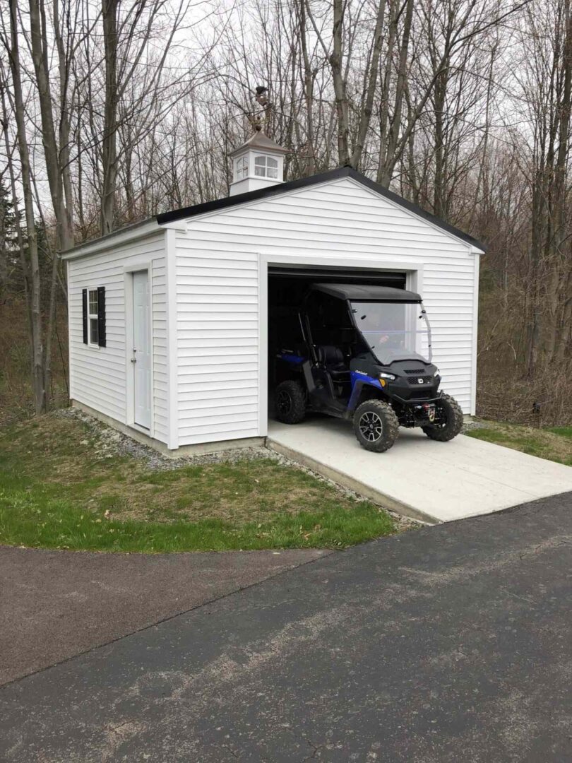 A white garage with a blue atv parked in it.