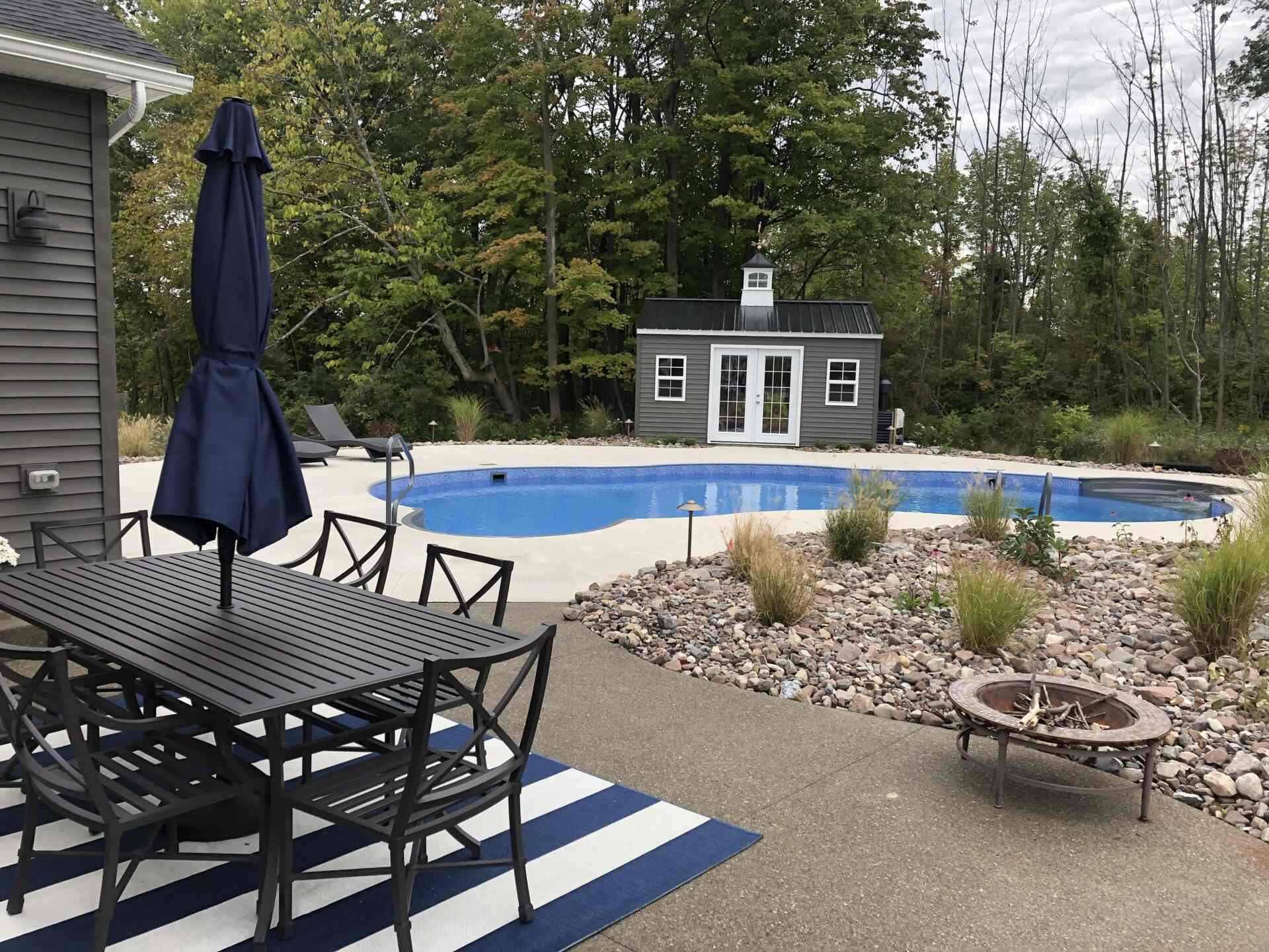 A table and chairs in front of a pool.