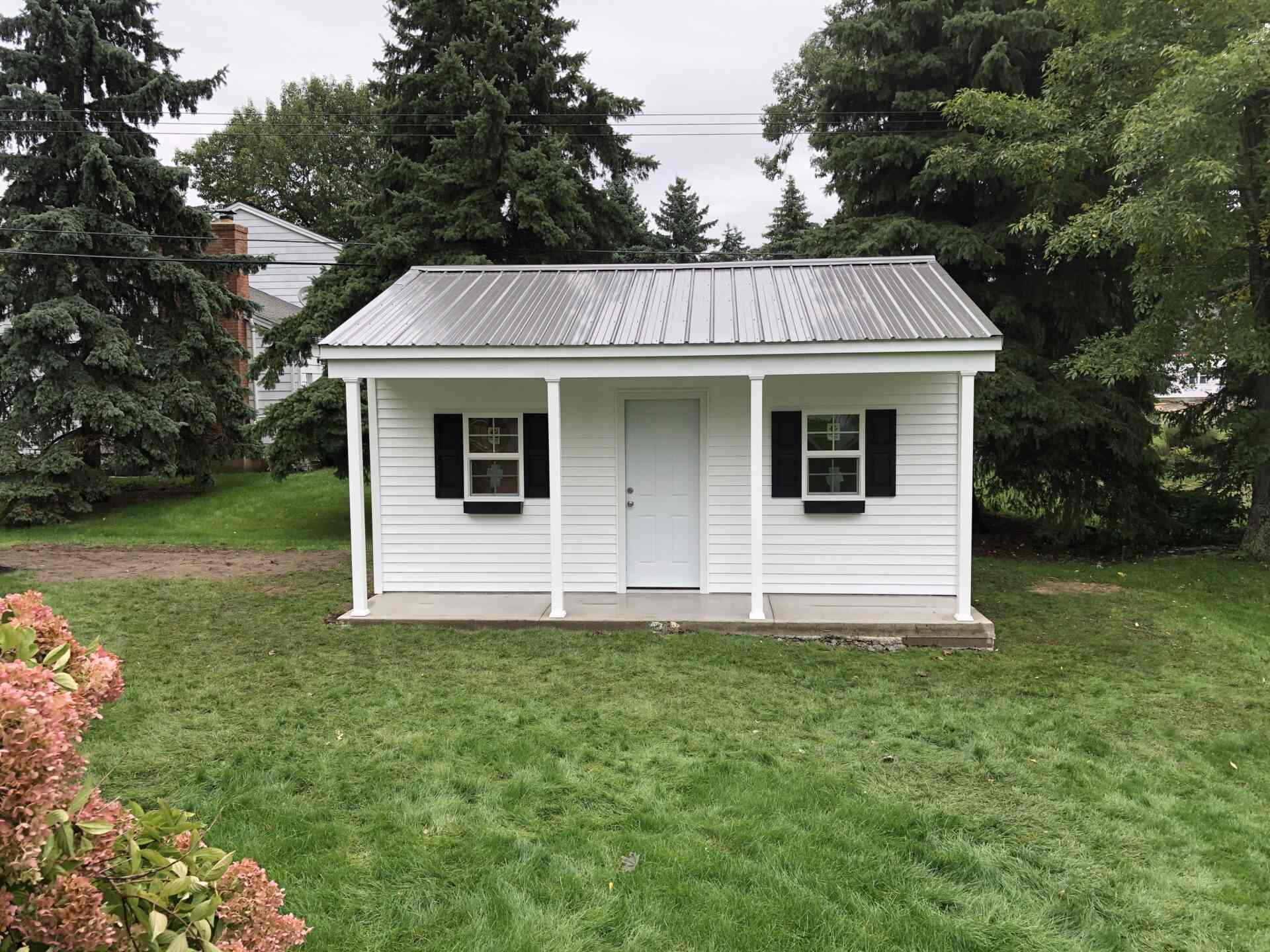 A small white shed with two windows and a metal roof.