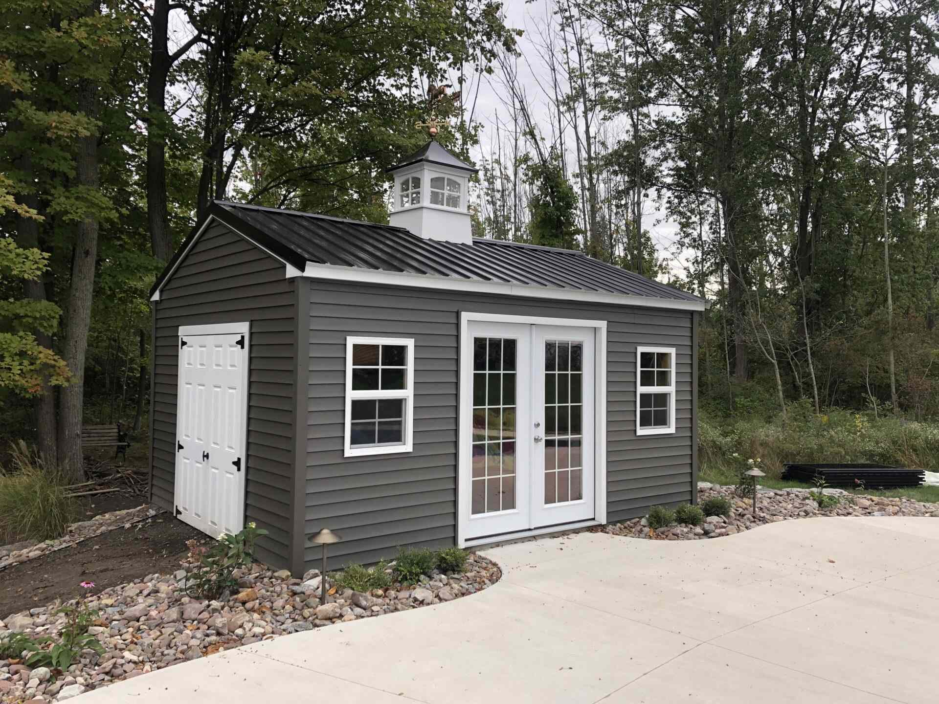 A gray shed with two windows and a door.