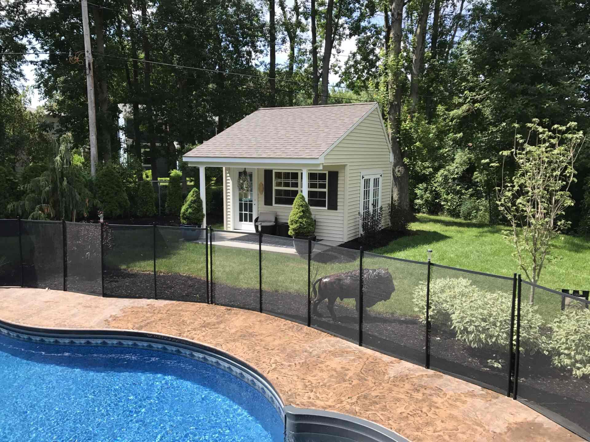 A pool with a house behind it and trees in the background.