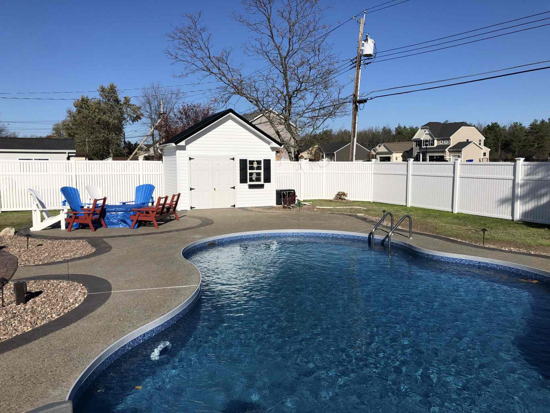 A pool with chairs and a white fence