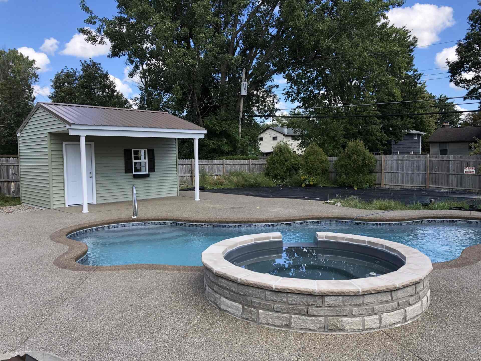 A pool with a fountain and a house in the background.
