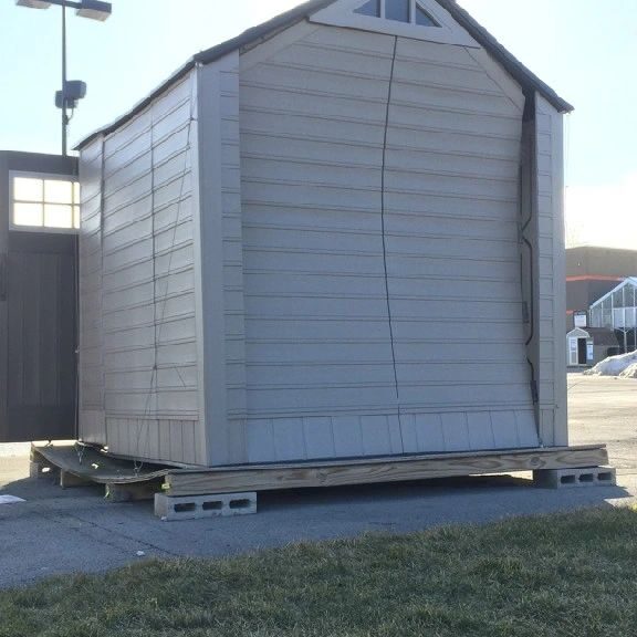 A large white shed sitting on top of some pallets.