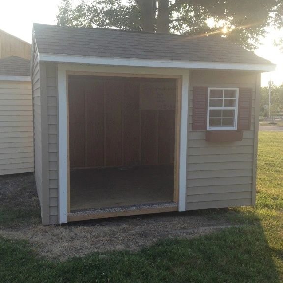 A shed with a window and shutters on the side.